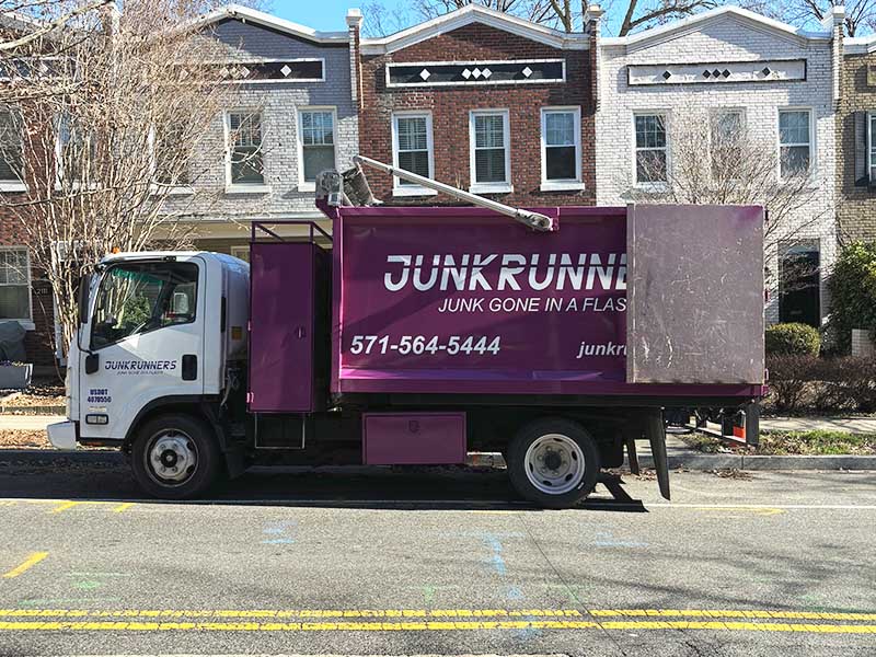 Junk Runners hauling truck parked in front of a row of townhouses.